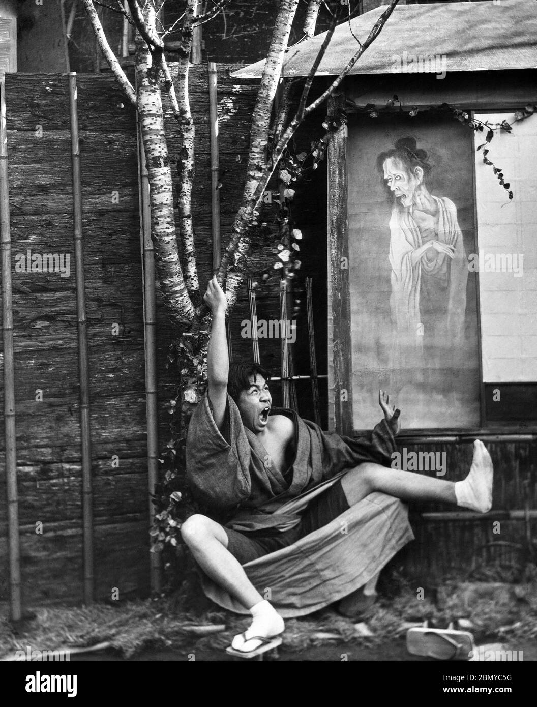 [ 1890er Japan - Japanischer Mann Angst vor Geist ] - Mann, der durch ein Gemälde eines Geistes überrascht. Aus einer Serie von Glasdias, die vom schottischen Fotografen George Washington Wilson (1823–1893) veröffentlicht (aber nicht fotografiert) wurden. Wilsons Firma war einer der größten Verleger von Fotodrucken in der Welt. 19. Jahrhundert Vintage Glas Rutsche. Stockfoto