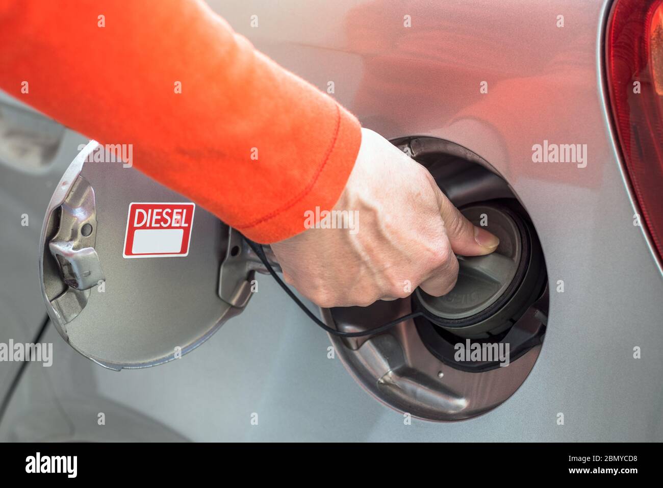 Nahaufnahme einer Frau, die den Tankdeckel eines Dieselwagens an einer Tankstelle öffnet Stockfoto