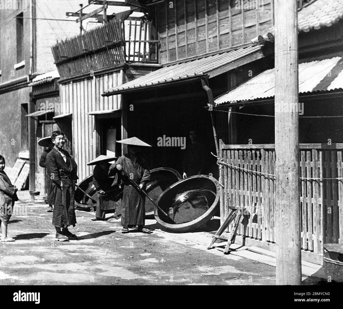 [ 1890er Japan - Japanischer Lack Workshop ] - Männer mit konischen Hüten (菅笠, sugegasa) Behandlung von Lack draußen in der Sonne. Aus einer Serie von Glasdias, die vom schottischen Fotografen George Washington Wilson (1823–1893) veröffentlicht (aber nicht fotografiert) wurden. Wilsons Firma war einer der größten Verleger von Fotodrucken in der Welt. 19. Jahrhundert Vintage Glas Rutsche. Stockfoto