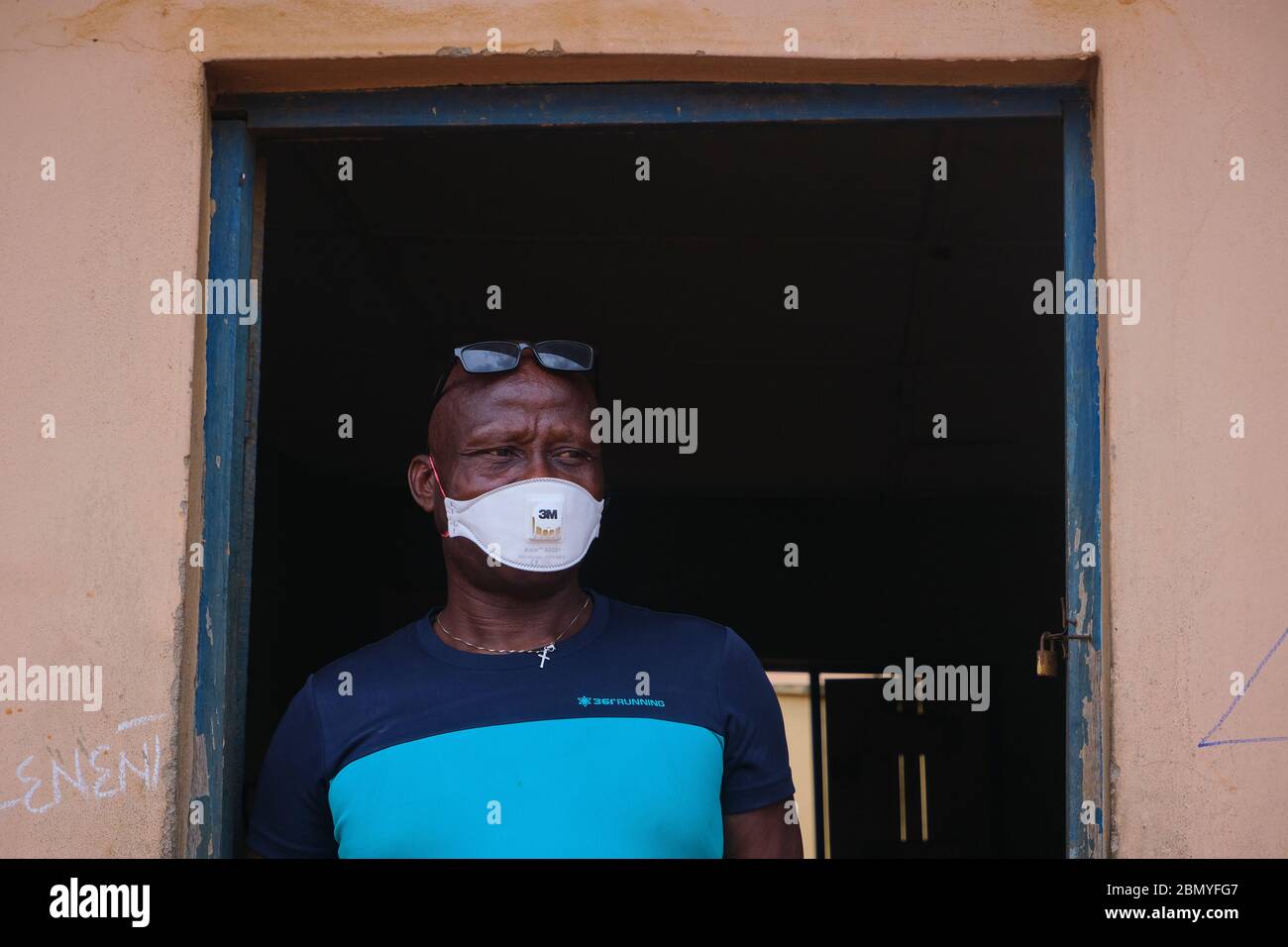 Ein Mann steht vor der Tür eines Klassenzimmers, wo ein Programm zur sozialen Distanzierung von Advocacy abgehalten wird, das von einer Regierungsbehörde in Lagos, Nigeria, abgehalten wird. Stockfoto