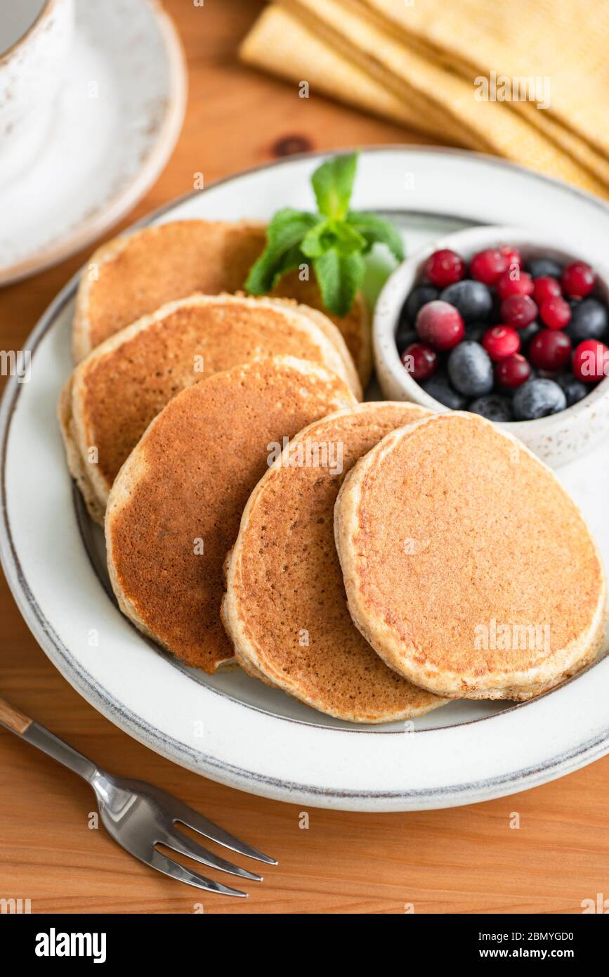 Buchweizen Pfannkuchen auf Teller mit Sommerbeeren serviert, Holztisch Hintergrund. Gesundes Frühstück Stockfoto