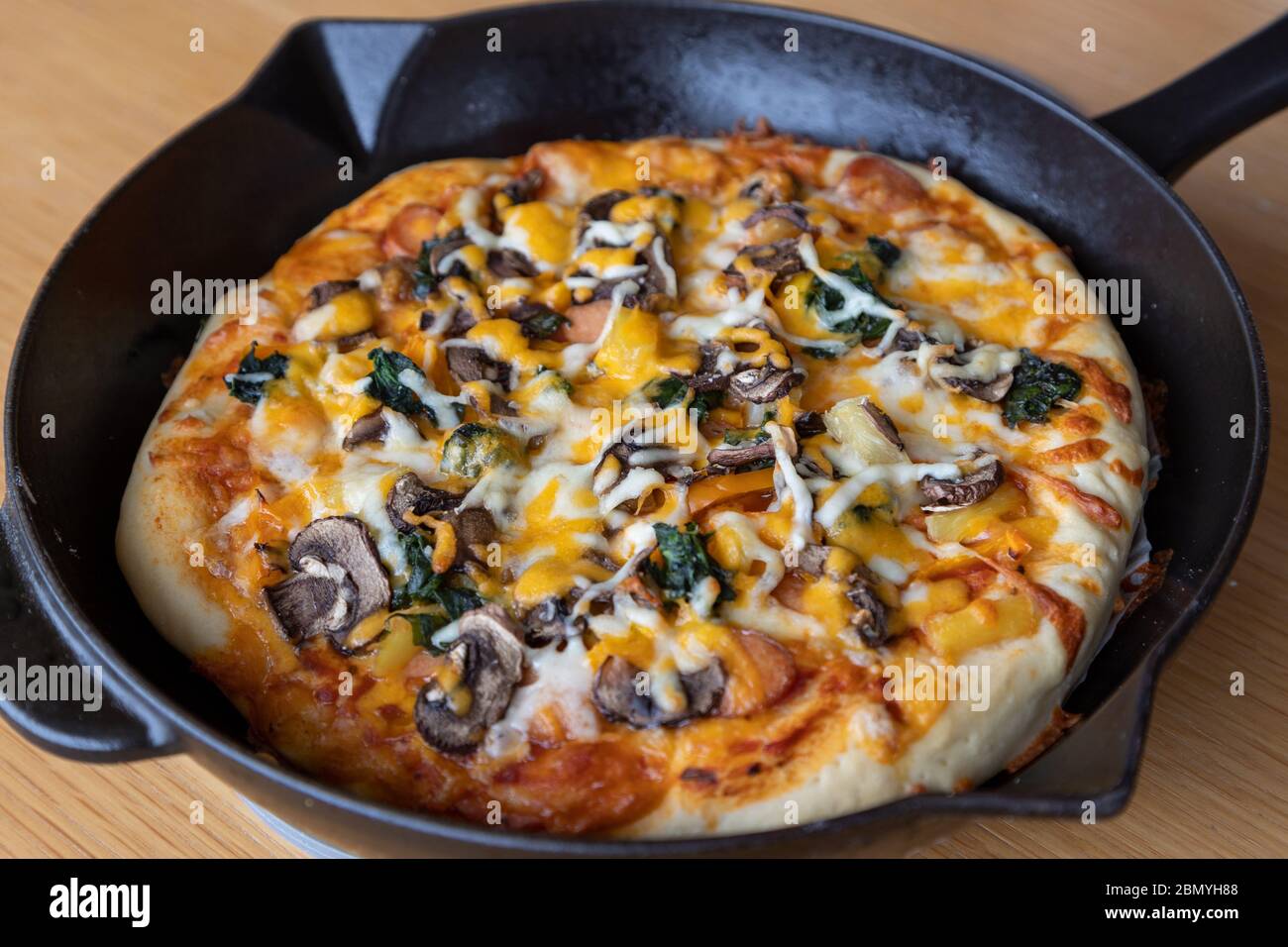 Nahaufnahme von hausgemachten vegetarischen Pizza mit Pilz, Spinat, Zwiebel, Käse, Paprika und verschiedene Gemüseauflagen und aromatische Kräuter Stockfoto
