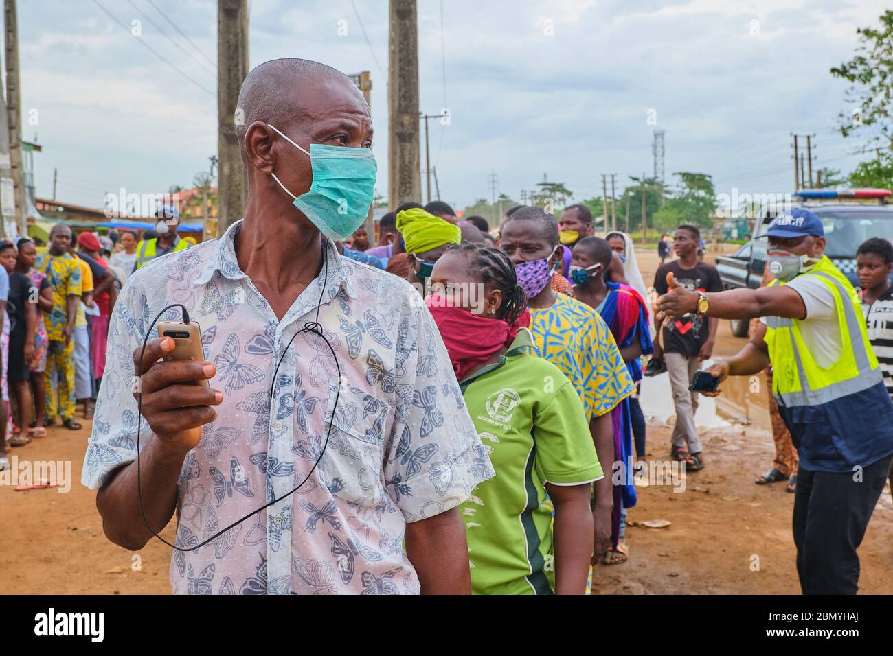 Regierungsbeamte versuchen, eine Menschenmenge zu kontrollieren, die während der Blockade der Covid-19-Pandemie in Lagos - Nigeria für Hilfspakete anstehen. Stockfoto