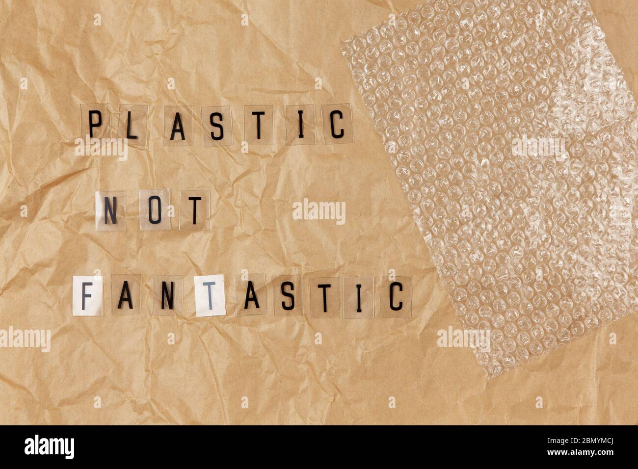 Luftblasenverpackung, Satz von Buchstaben auf transparenter Basis Kunststoff nicht fantastisch auf braun zerknittert Bastelpapier. Eco, Zero Waste Konzept. Flach liegend, Draufsicht. Stockfoto