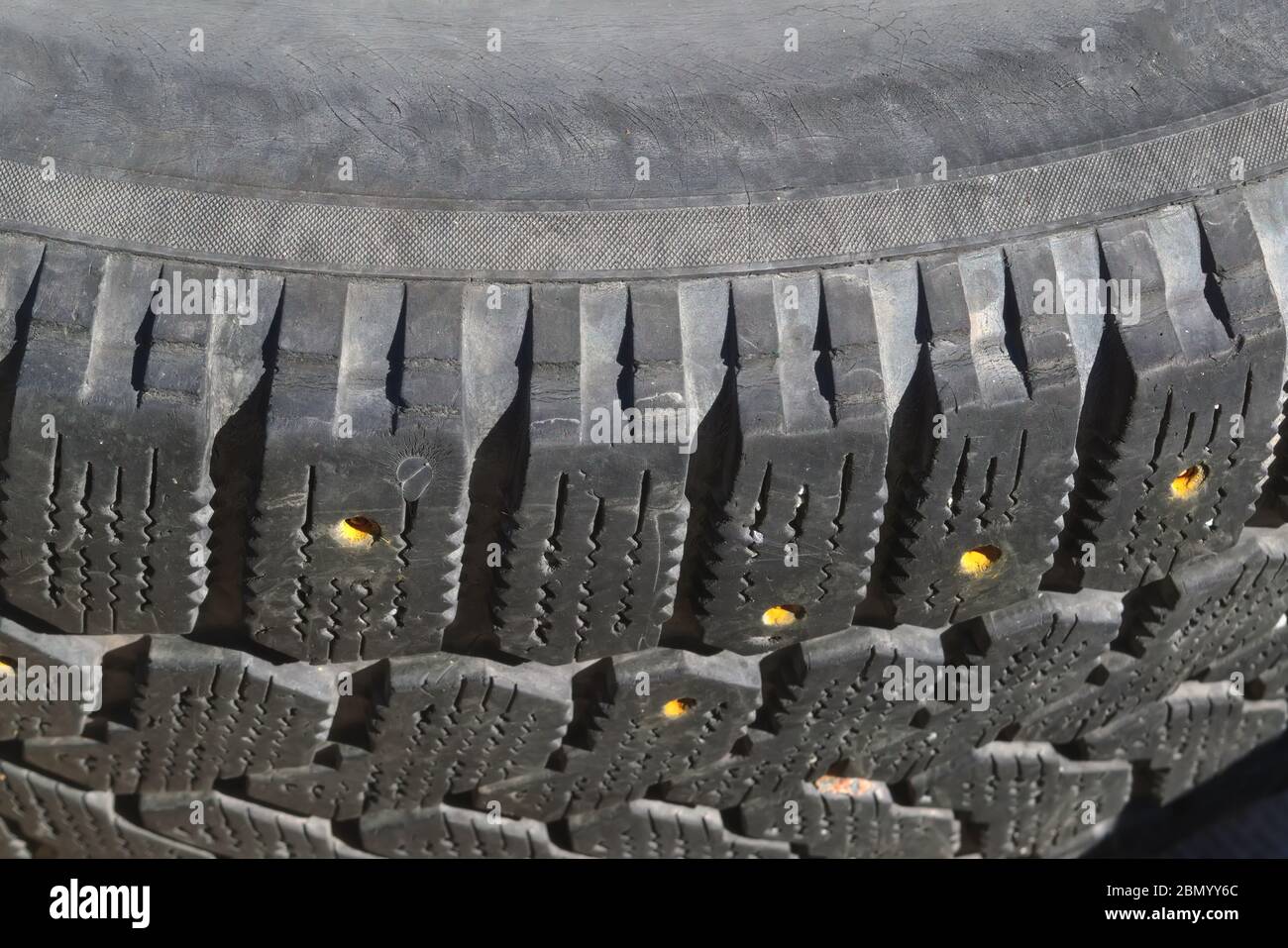 Lauffläche eines alten Auto-Winterreifen mit heruntergefallenem Spikes Nahaufnahme. Abgenutzte Winterreifen. Stockfoto