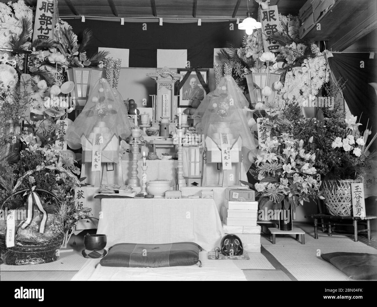 [ 1930er Jahre Japan - Buddhistischer Beerdigungsdienst ] - Ausstellung bei einem buddhistischen Beerdigungsdienst, ca. 1930er Jahre. Die Ausstellung umfasst Blumenarrangements, Geschenke, Kerzen, religiöse Opfer, ein Porträt des Verstorbenen und ein ihai (位牌), eine Gedenktafel mit dem neuen buddhistischen Namen der Person für das Jenseits. 20. Jahrhundert Vintage Glas negativ. Stockfoto