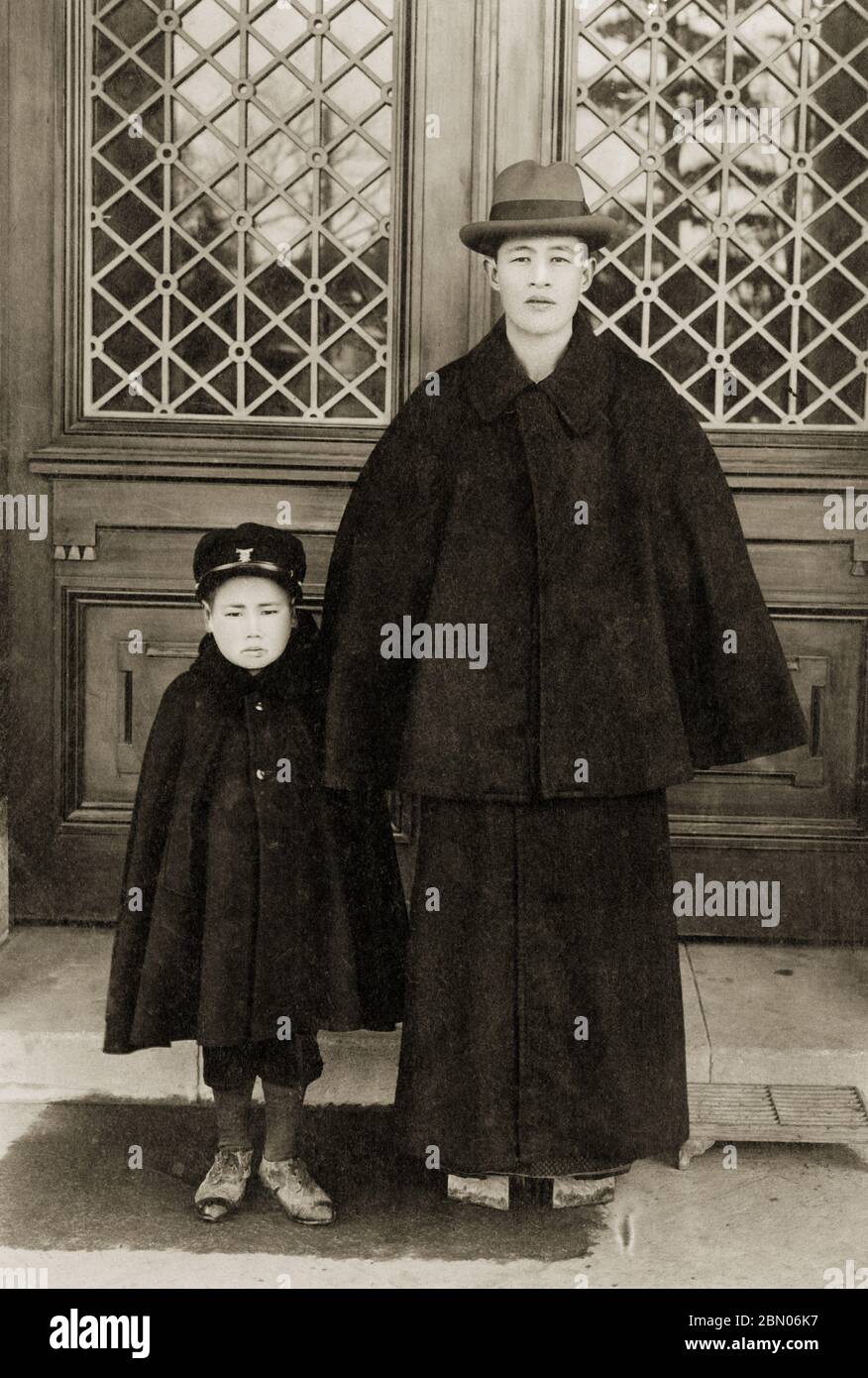 [ Japan der 1920er Jahre - Vater und Sohn in Tonbi Mantel ] - EIN Vater und sein Sohn, beide tragen einen Inverness Stil Tonbi Mantel (とんびコート). Der Tonbi Mantel, eine perfekte Fusion aus japanischen und westlichen Stilen, wurde erstmals um 1887 (Meiji 20) eingeführt, erreichte aber seinen Höhepunkt der Popularität während Taisho (1912-1926) und Early Showa (1926-1989). Seine große Popularität ist teilweise auf die Tatsache zurückzuführen, dass es leicht mit traditionellen japanischen Kleidung getragen werden konnte, die große Ärmel zeigte. Der Mantel war besonders bei Intellektuellen beliebt. Silberdruck mit Gelatine aus dem 20. Jahrhundert. Stockfoto