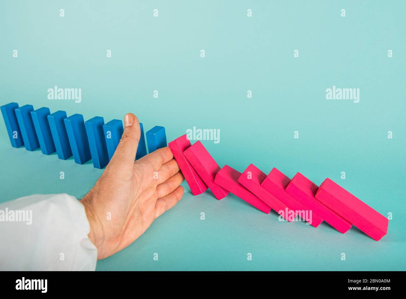 Konzept der covid19 Coronavirus Pandemie mit fallenden Kette wie ein Domino-Spiel. Ansteckung und Infektionsverlauf wurden durch eine Hand eines Arztes gestoppt. Zyan Stockfoto