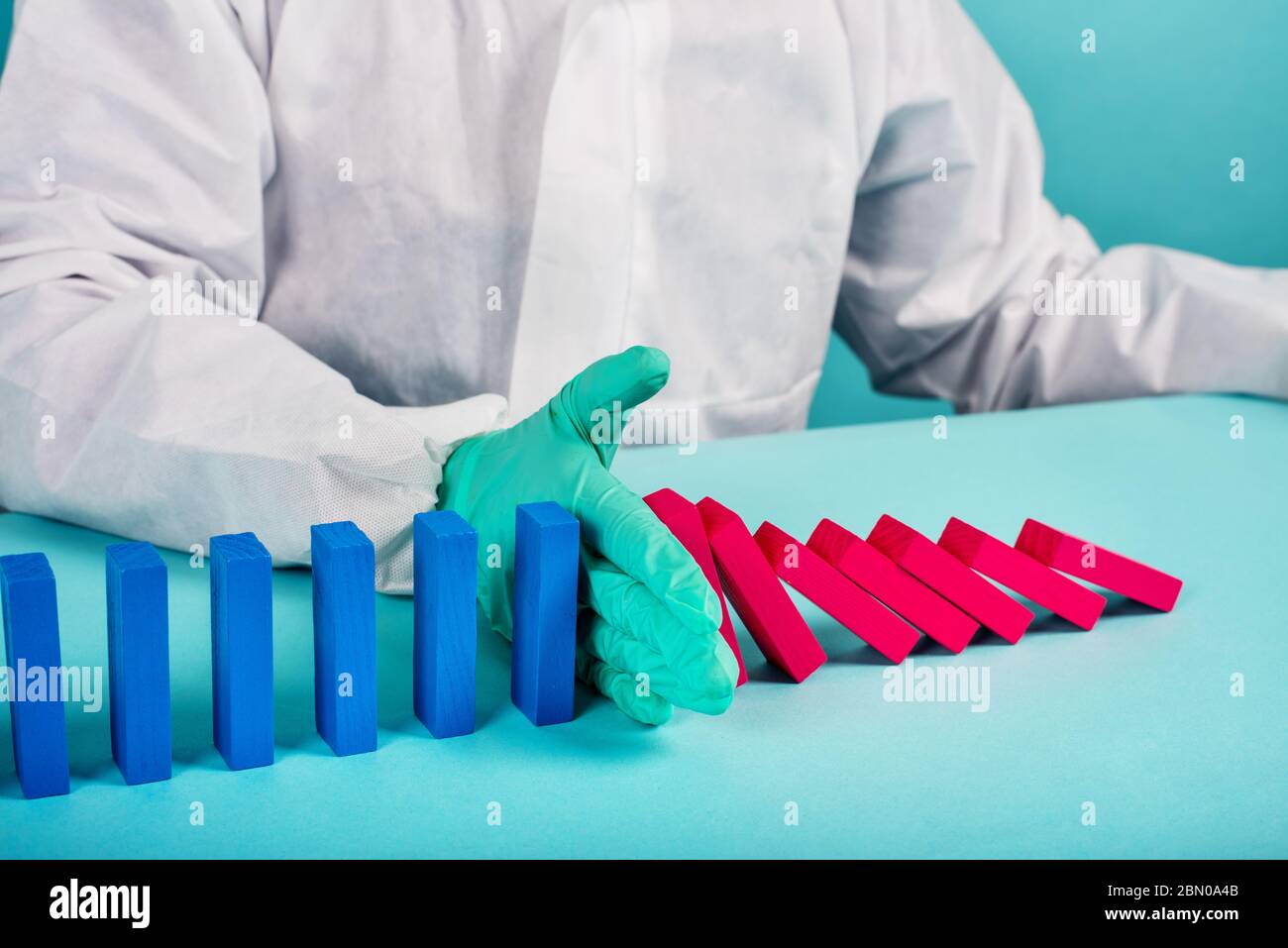 Konzept der covid19 Coronavirus Pandemie mit fallenden Kette wie ein Domino-Spiel. Ansteckung und Infektionsverlauf wurden durch eine Hand eines Arztes gestoppt. Zyan Stockfoto