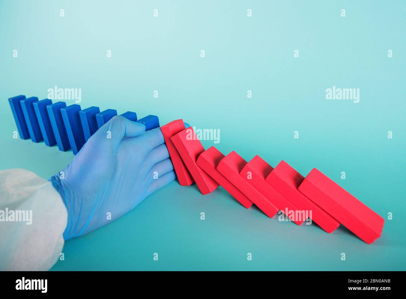Konzept der covid19 Coronavirus Pandemie mit fallenden Kette wie ein Domino-Spiel. Ansteckung und Infektionsverlauf wurden durch eine Hand eines Arztes gestoppt. Zyan Stockfoto