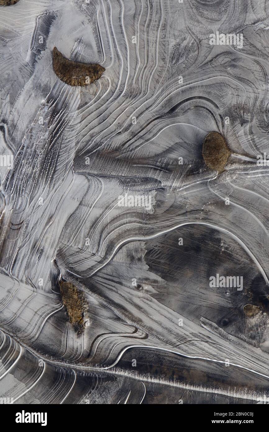 Nahaufnahme von Eisformationen mit eleganten Linien und Flussgestein während des Frühlings schmelzen entlang des Yukon River. Das kreative Chaos der Natur und die zufällige Eleganz Stockfoto