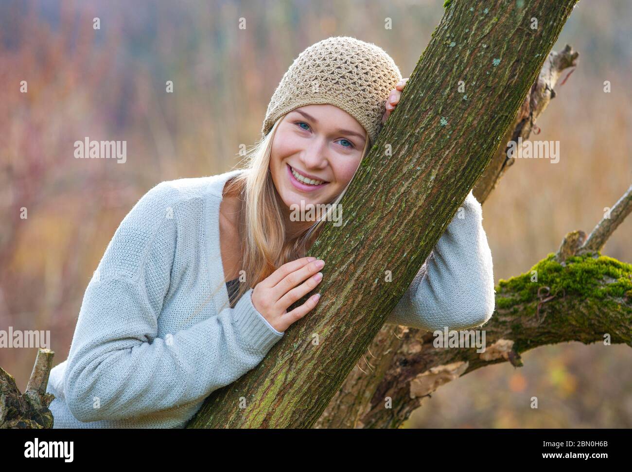 Mädchen mit Mütze, die sich im Herbst an einen Baum lehnt, 17 Jahre, Oberösterreich, Österreich Stockfoto