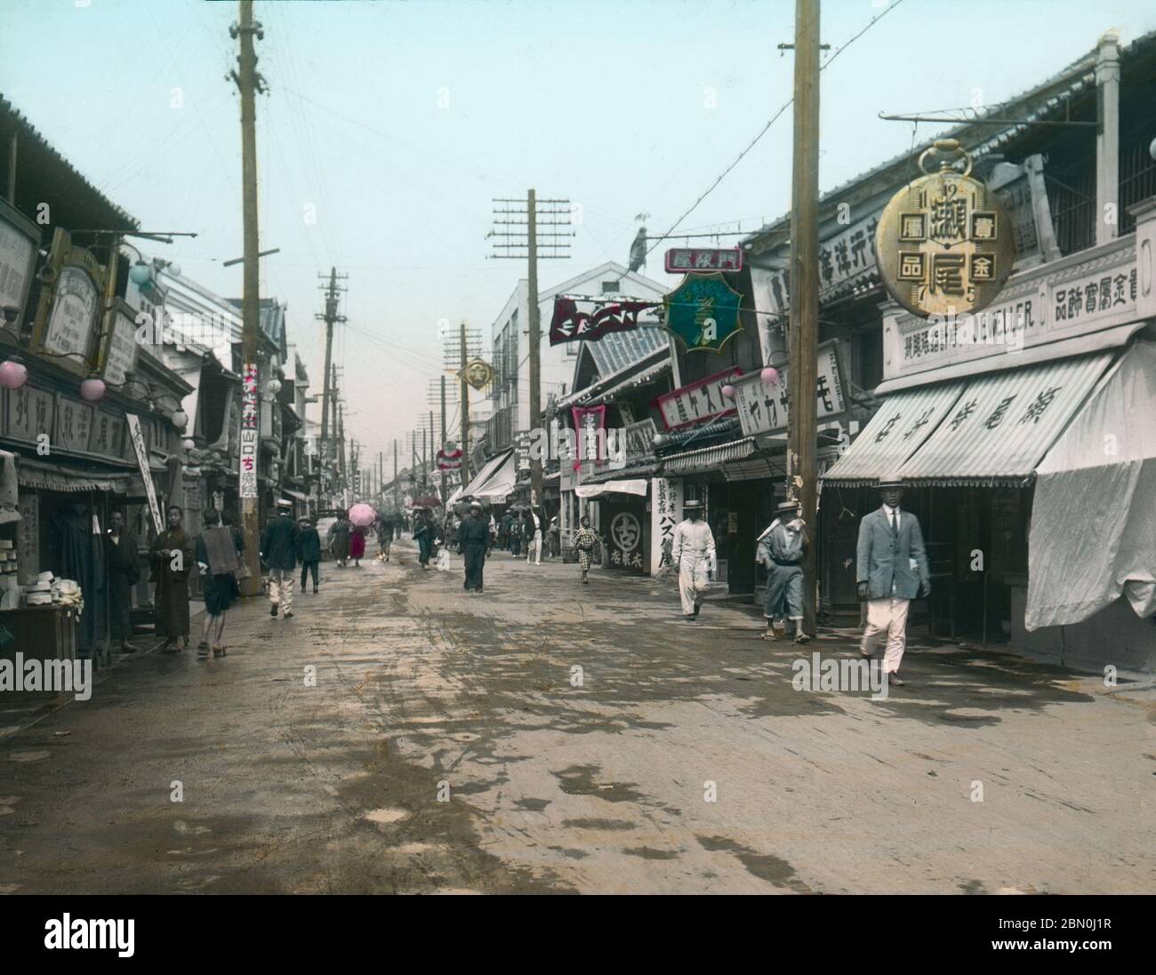 [ 1910 Japan - Motomachi Shopping Street, Kobe ] - Käufer, meist Männer in westlicher Kleidung und Strohboaterhätzen, gehen vor den Geschäften in Motomachi in Kobe, Präfektur Hyogo. 19. Jahrhundert Vintage Glas Rutsche. Stockfoto