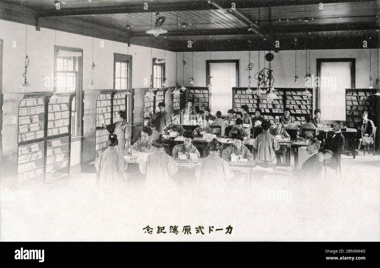 [ 1906 Japan - Japanische Büroangestellte ] - Büroangestellte bei der Arbeit mit einem modernen Kartensystem bei der japanischen Postgeldordnung und Postsparverwaltung (郵便為替貯金管理所, Yubin Kawase Chokin Kanrisho), 1906 (Meiji 39). Gedenkkarte (第一回決算記念会) veröffentlicht am 8. Juli 1906. Im selben Jahr wurden erstmals bundesweit Geldtransfers zwischen Postsparkonten möglich. Vintage-Postkarte des 20. Jahrhunderts. Stockfoto