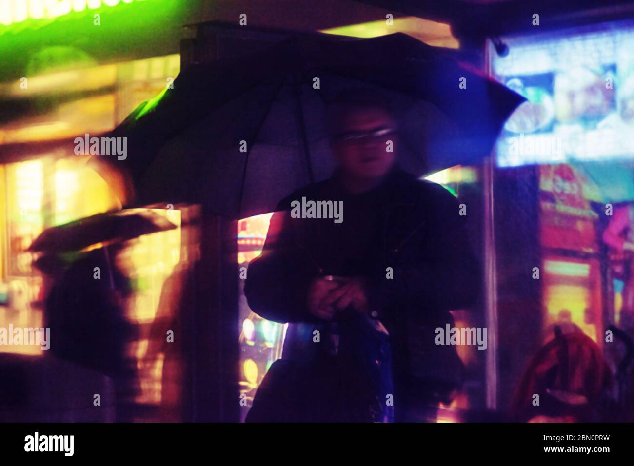 Verschwommenes dramatisches Szenenkonzept des alten Mannes mit Regenschirm bei heftiger Regenzeit. Selektiver Fokus und geringe Schärfentiefe, farbgetönte Farben. M Stockfoto