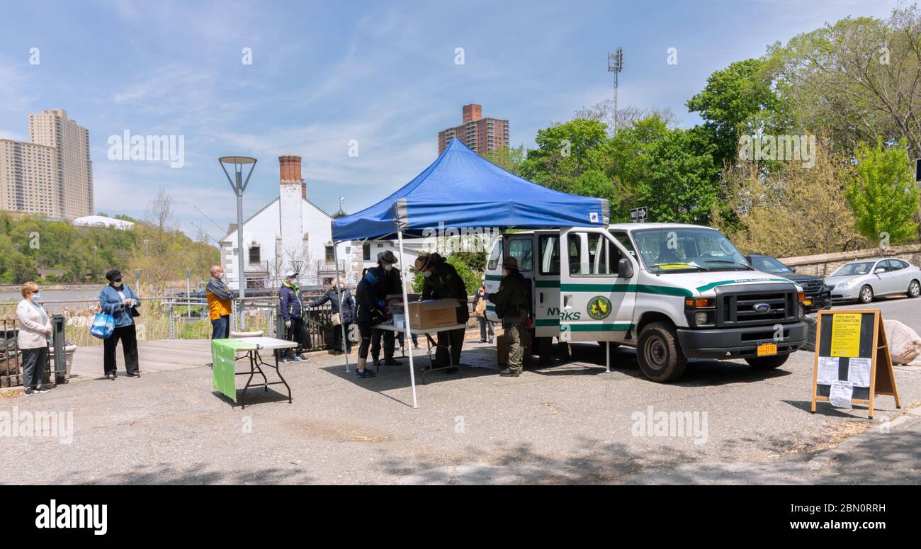 Die Menschen warten in der Schlange auf kostenlose Gesichtsmasken, die während des Coronavirus oder der Covid-19-Pandemie vom NYC Department of Parks im Inwood Hill Park verteilt werden Stockfoto