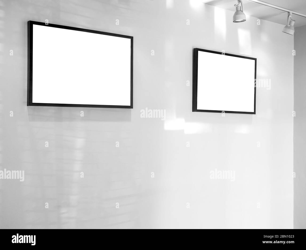 Zwei weiße leere Rahmen mit Scheinwerfer auf weißen Wand Hintergrund in der Kunstgalerie. Stockfoto