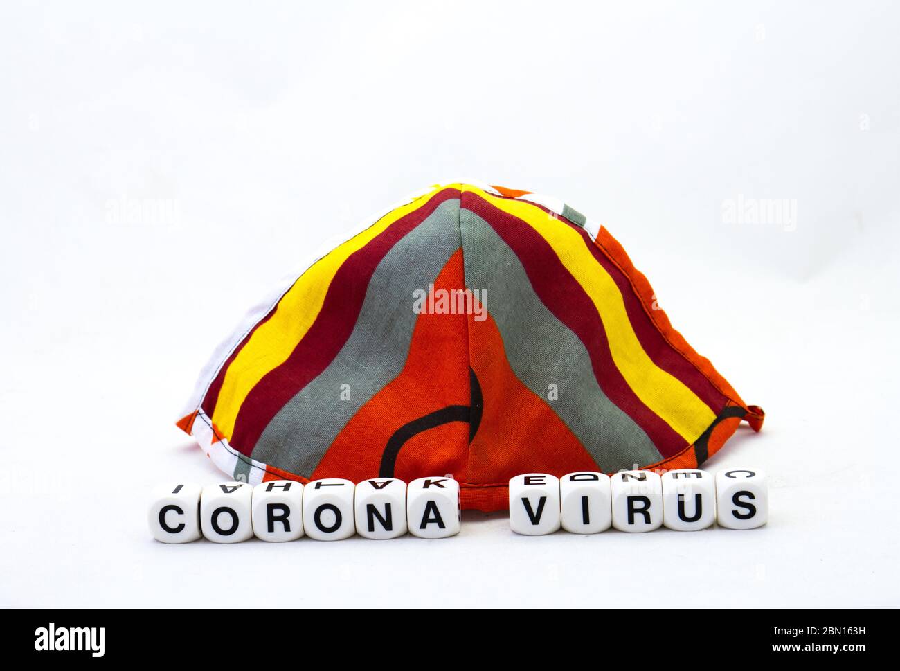 Eine bunte Stofffacemask und die Begriffe Corona und Virus isoliert auf einem klaren Hintergrundbild mit Kopierraum im horizontalen Format Stockfoto