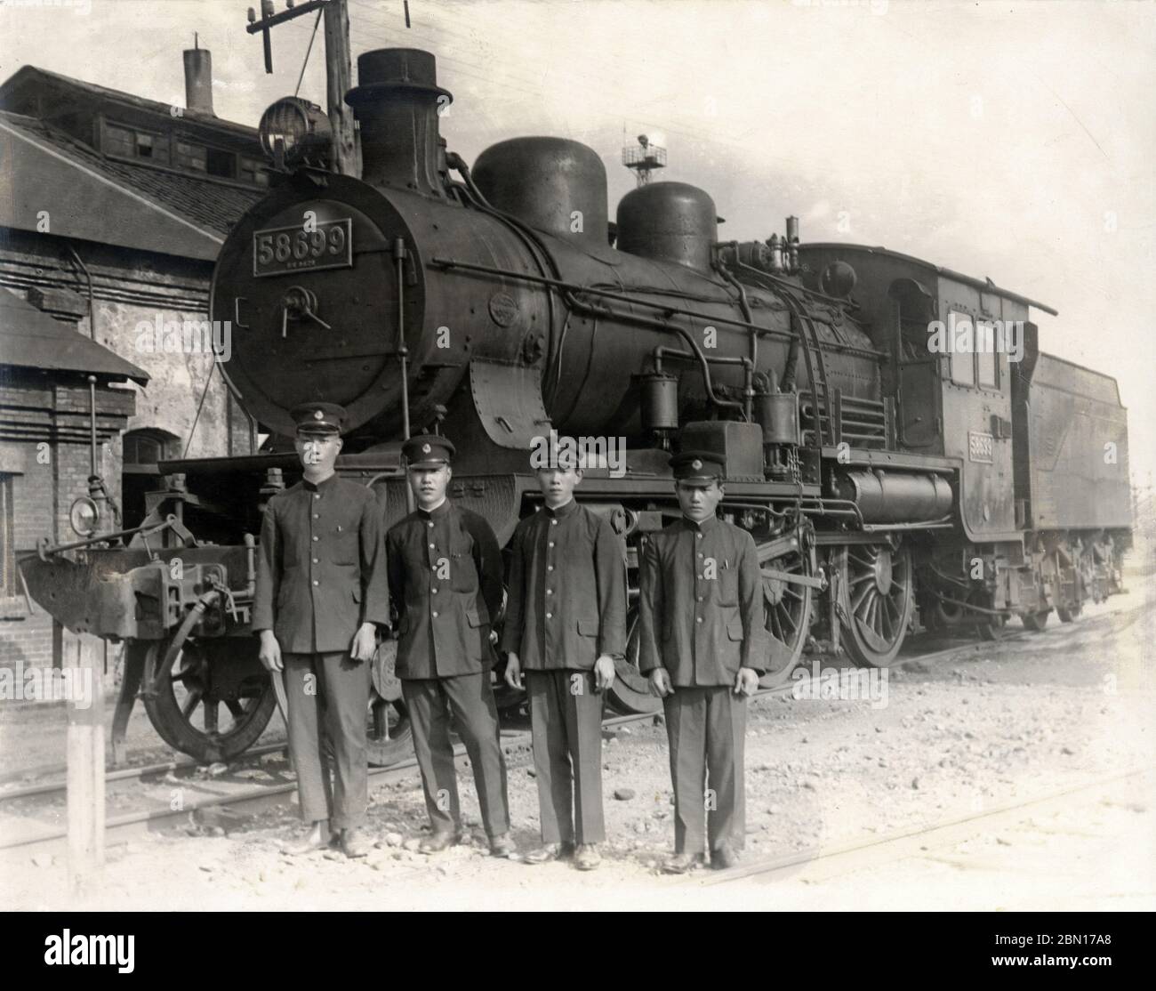 [ 1931 Japan - Kaiserlicher Zug ] - Gedenkfoto von Eisenbahnern vor einer Dampflokomotive der Baureihe 8620 (8620形) mit der Nummer 58699. Das Foto ist vom 12. August 1931 (Showa 6). Der Bildunterschrift zufolge wurde die Lokomotive benutzt, um den kaiserlichen Zug von Takahito, Prinz Mikasa (三笠宮崇仁親王, 1915–2016), zu ziehen. Silberdruck mit Vintage-Gelatine aus dem 20. Jahrhundert. Stockfoto