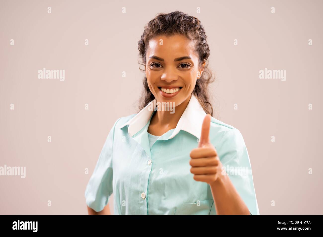 Porträt der jungen glücklichen Krankenschwester, die Kamera anschaut und lächelt. Stockfoto