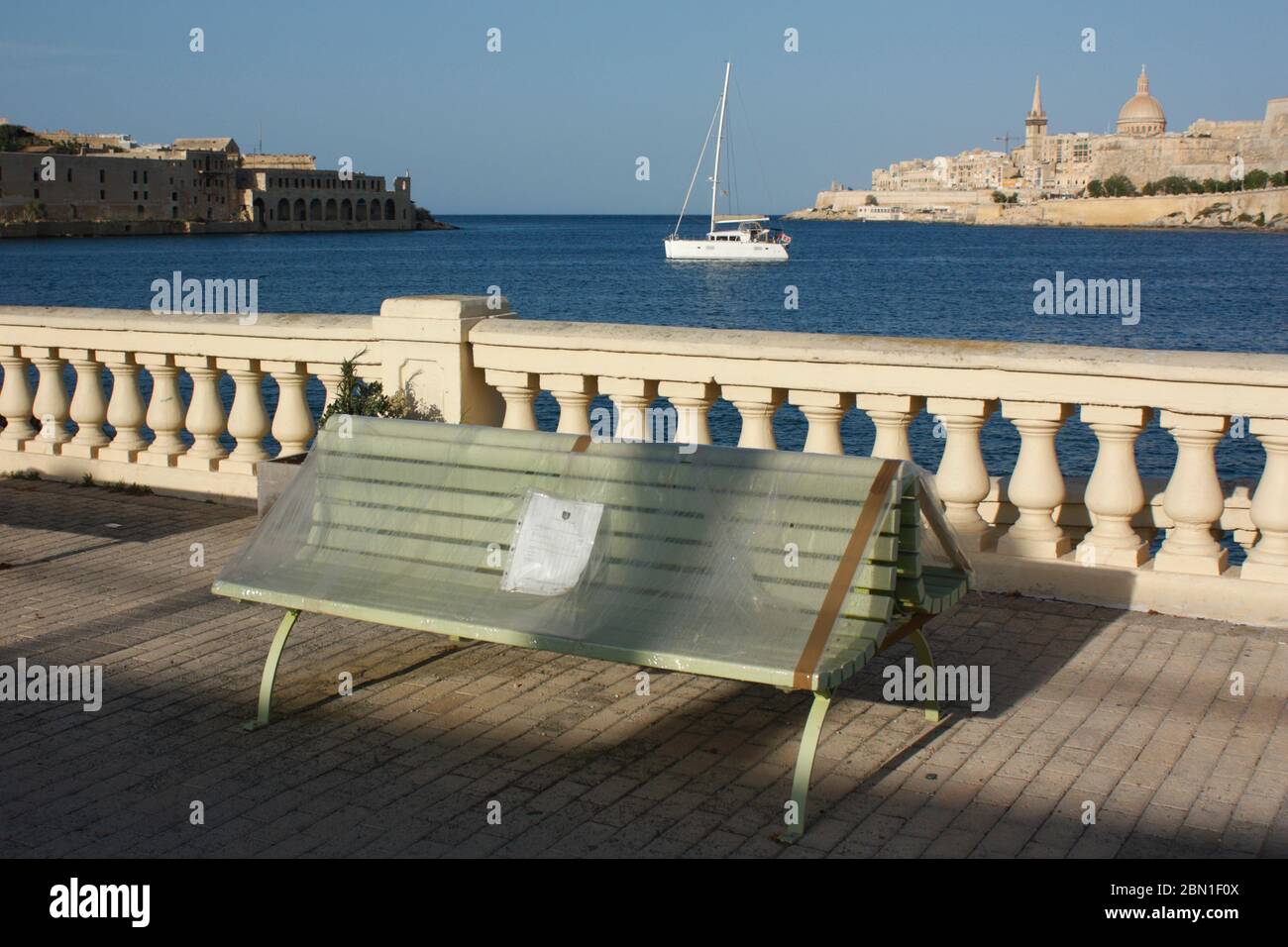 COVID-19 und Coronavirus. Öffentliche Bank mit Kunststofffolie in Malta, Europa, um soziale Distanzierung zu erzwingen bedeckt. Auswirkungen der Pandemie auf Reisen. Stockfoto