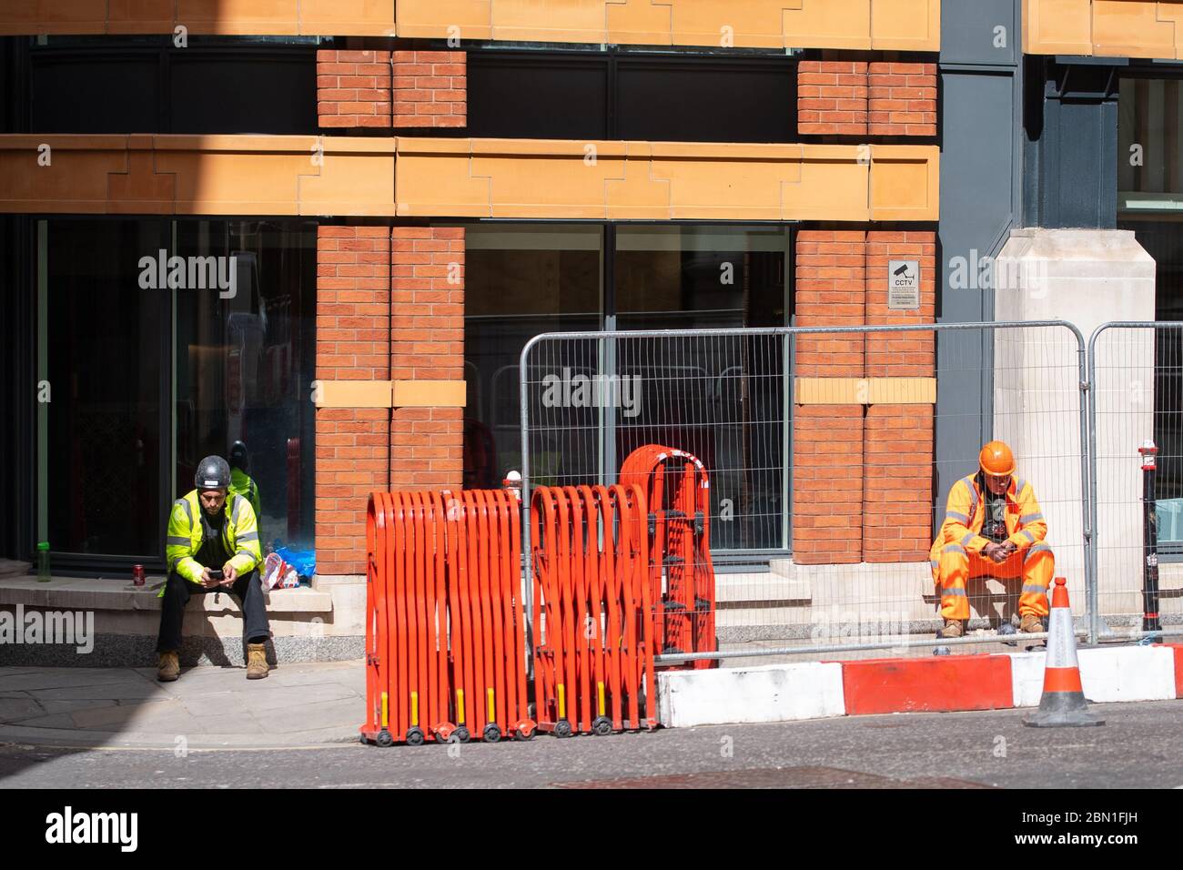 Zwei Bauarbeiter sitzen während einer Pause auf einer Baustelle im Zentrum Londons auseinander, wie Premierminister Boris Johnson sagte, dass Menschen, die nicht von zu Hause aus arbeiten können, "aktiv ermutigt" werden sollten, wieder an ihren Arbeitsplatz zurückzukehren. Stockfoto