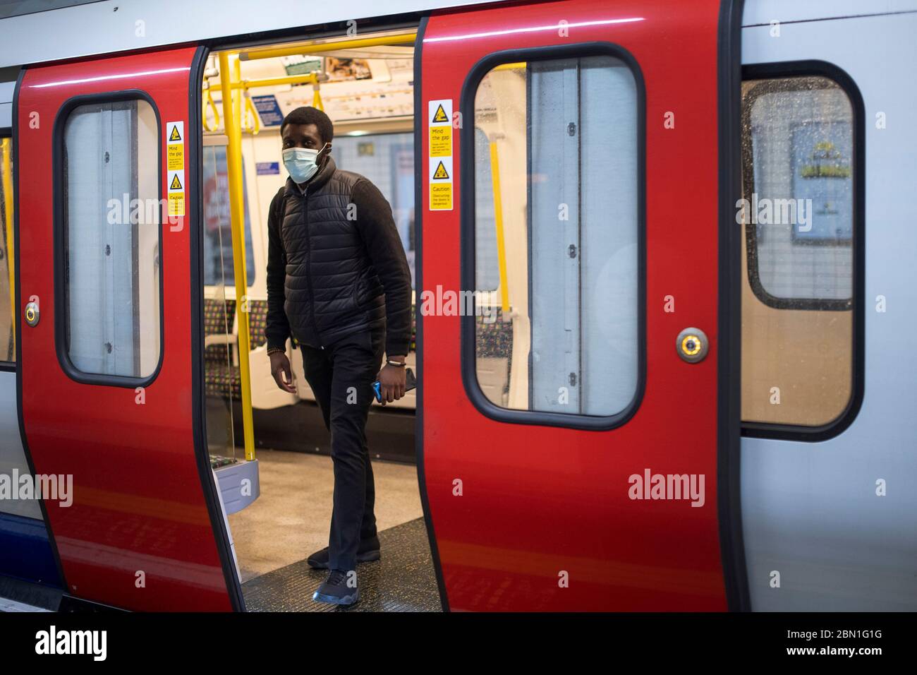 Ein Mann trägt während der üblichen Hauptverkehrszeit am Abend eine Gesichtsmaske auf der Linie des Londoner U-Bahndistrikts, während Großbritannien weiterhin in der Sperrstunde bleibt, um die Ausbreitung des Coronavirus einzudämmen. Stockfoto