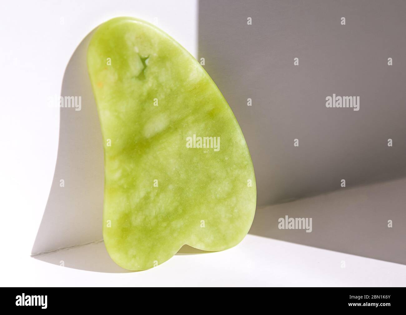 Gua Sha Werkzeug aus natürlichem Edelstein aus grüner Jade auf weißem Hintergrund Stockfoto