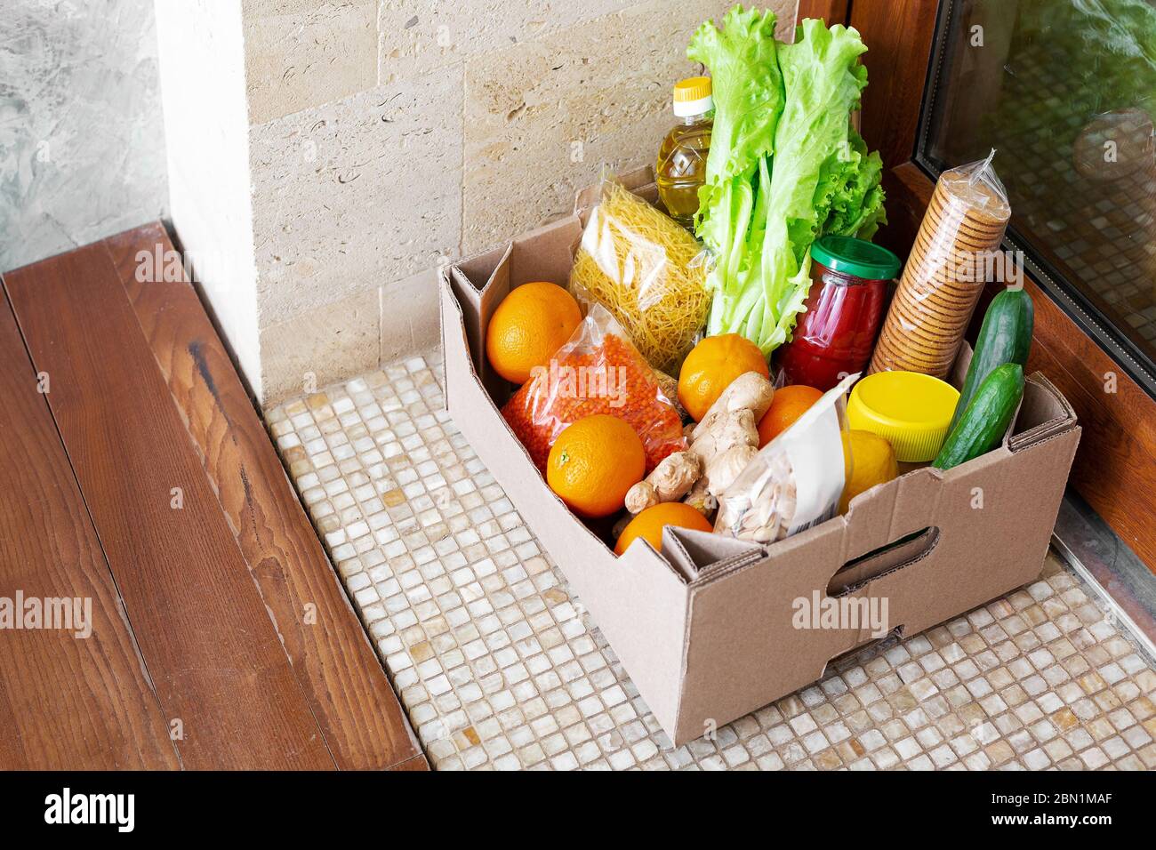 Spendenbox mit Nahrung während der covid Quarantäne. Die Lieferung der Food Box liegt direkt vor der Tür. Kontaktlose Zustellung nach Hause, sicheres Einkaufen Stockfoto