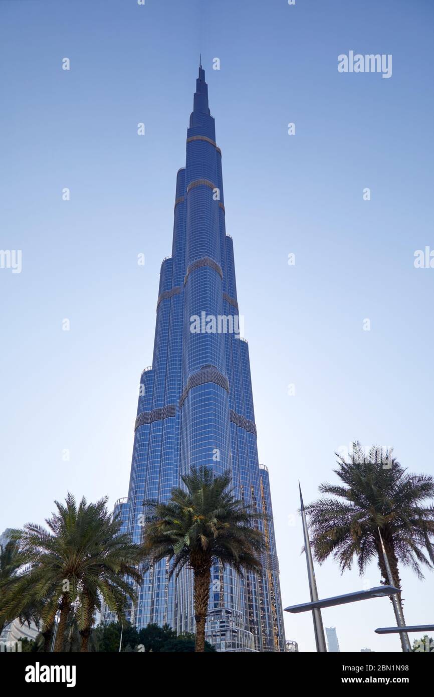 DUBAI, VEREINIGTE ARABISCHE EMIRATE - 22. NOVEMBER 2019: Burj Khalifa Wolkenkratzer aus tiefem Winkel, klarer blauer Himmel mit Palmen Stockfoto