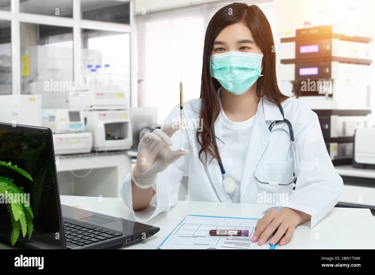 Asiatischer Arzt hält eine Spritze, Blutprobe Reagenzglas für covid-19 Analyse mit Patientenakte auf dem Schreibtisch im Labor. Labor Analyse für die Prüfung Stockfoto