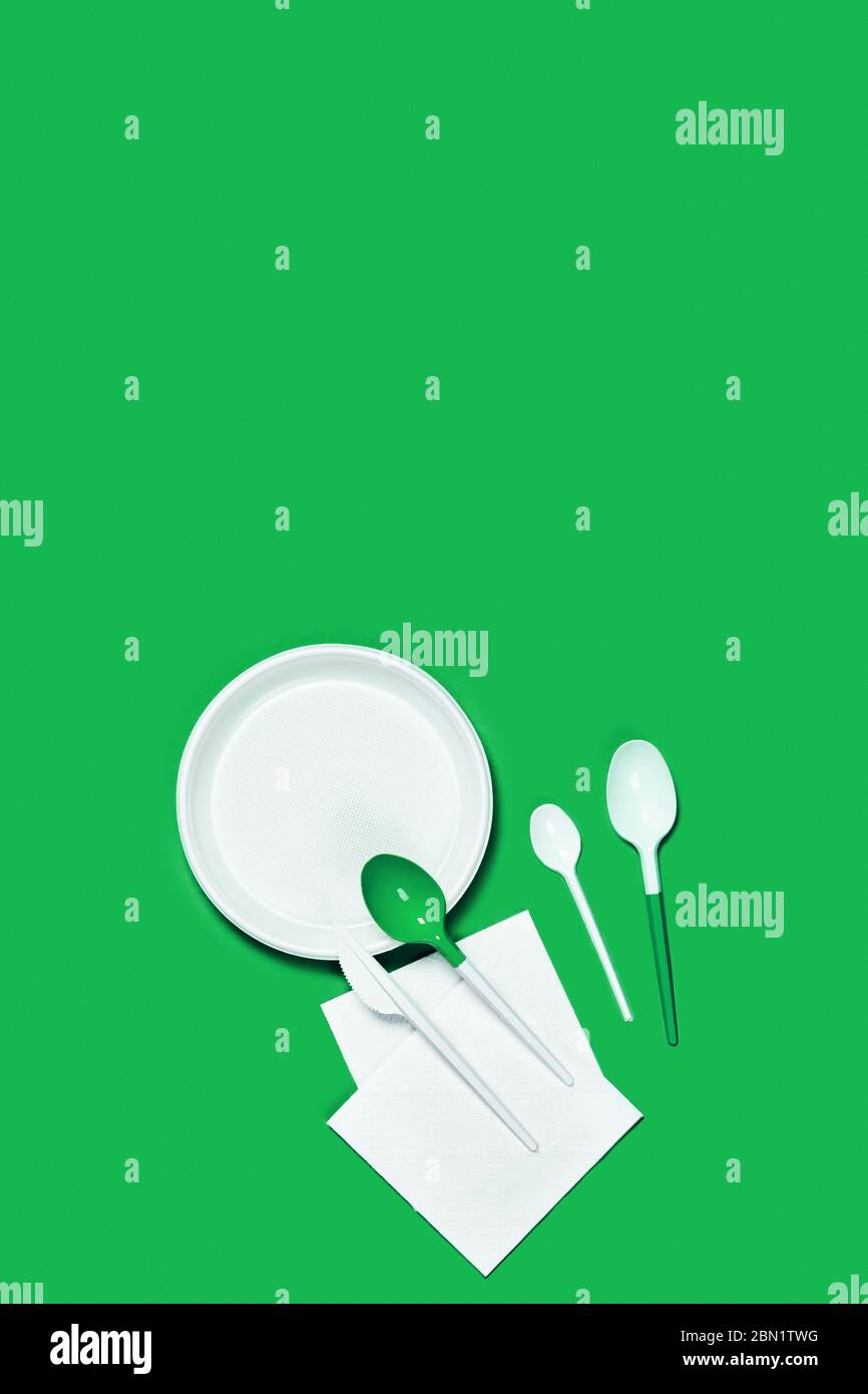 Abbildung der weißen Kunststofflöffel und -Platten auf blauem Hintergrund. Flaches Layout, Draufsicht, Kopierbereich. Stockfoto
