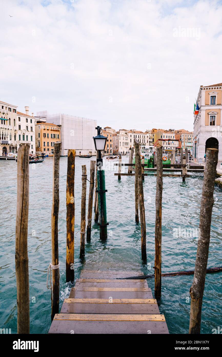 Holzsteg für Boote und Gondeln in Italien, in Venedig. Eine Holztreppe geht unter Wasser, vertikale Haufen von Baumstämmen. Grand Canal mit azurblau Stockfoto