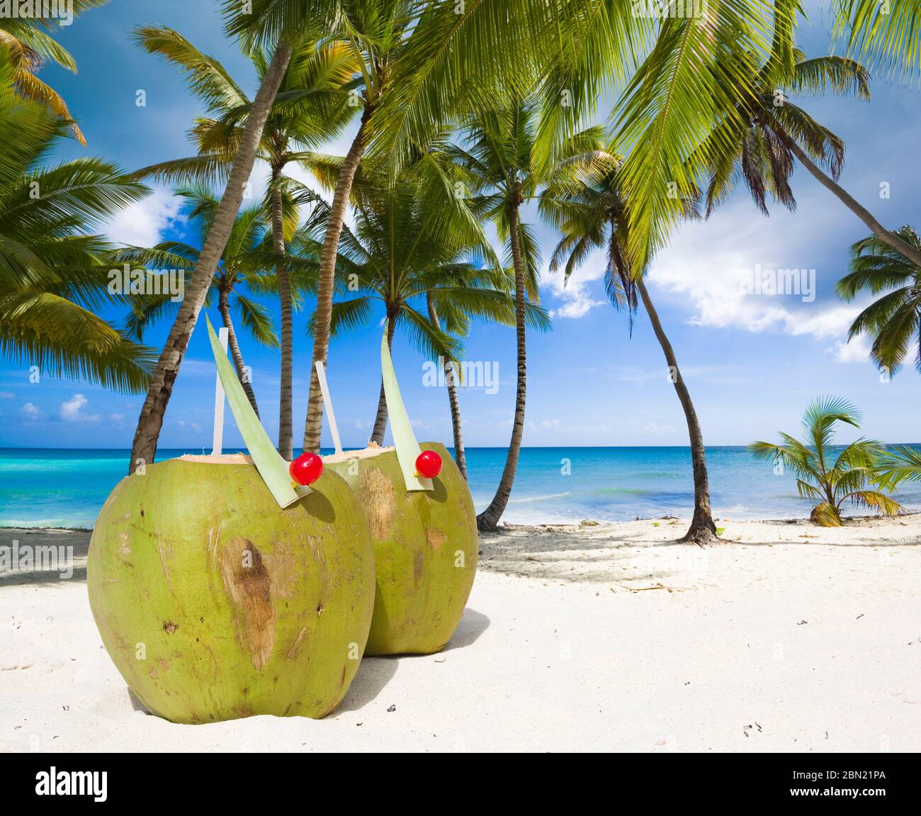 Kokosnussgetränke auf weißem Sand des tropischen Strandes, türkisfarbenes Wasser des Meeres im Hintergrund. Sommerurlaub Konzept Stockfoto