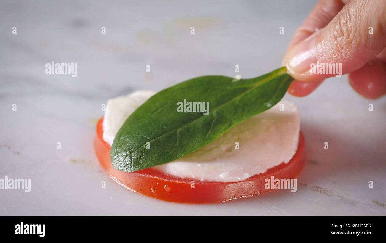 Sandwich vorbereiten, Turm Caprese Salat. Gesunder vegetarischer Salat mit geschnittenen Tomaten, Gurken, Mozzarella und Basilikum. Frisches, natürliches Sommerdinner. Stockfoto