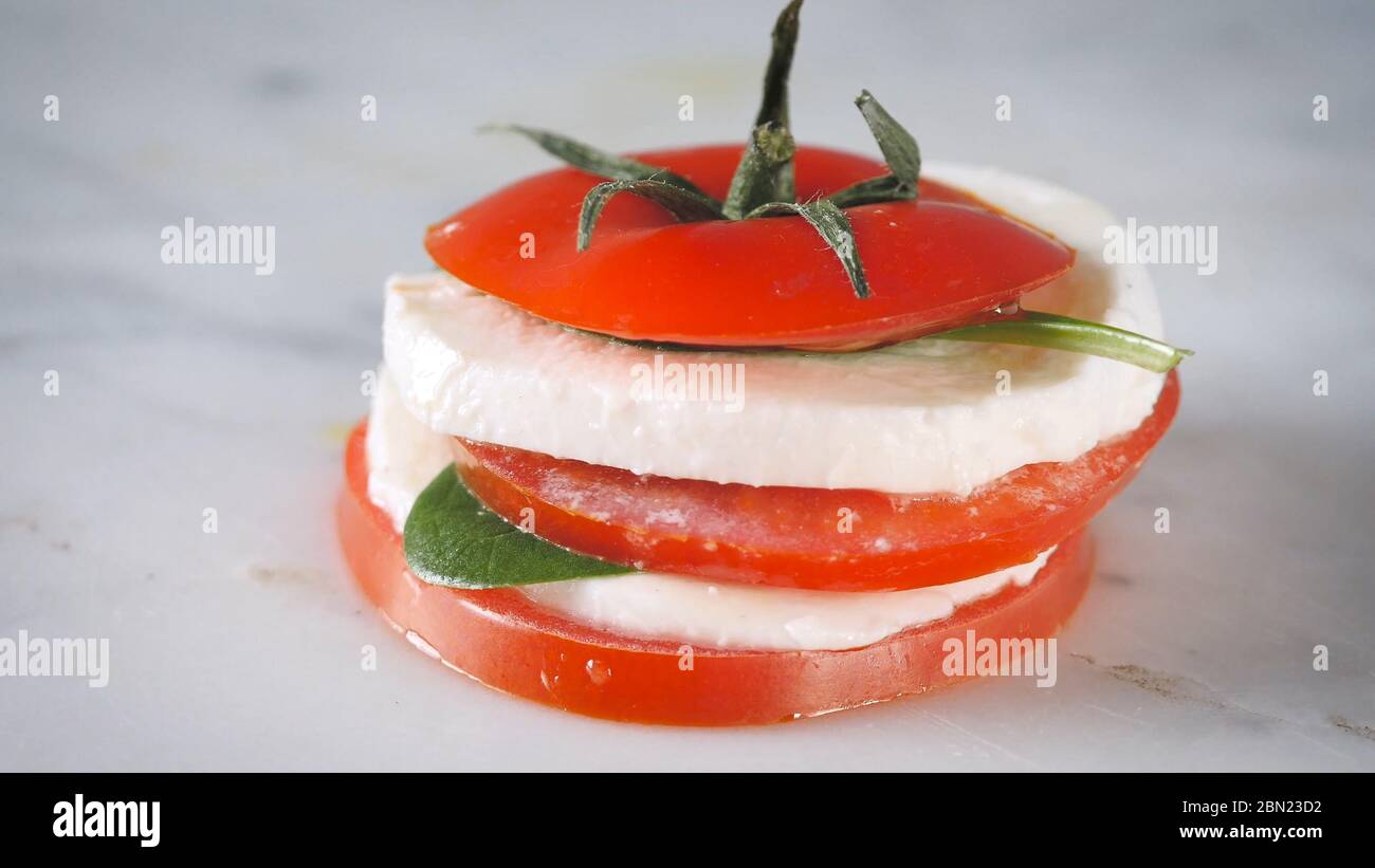 Salat aus Turmkaprese. Gesunder vegetarischer Salat mit geschnittenen Tomaten, Gurken, Mozzarella und Basilikum. Frisches, natürliches Sommerdinner. Stockfoto