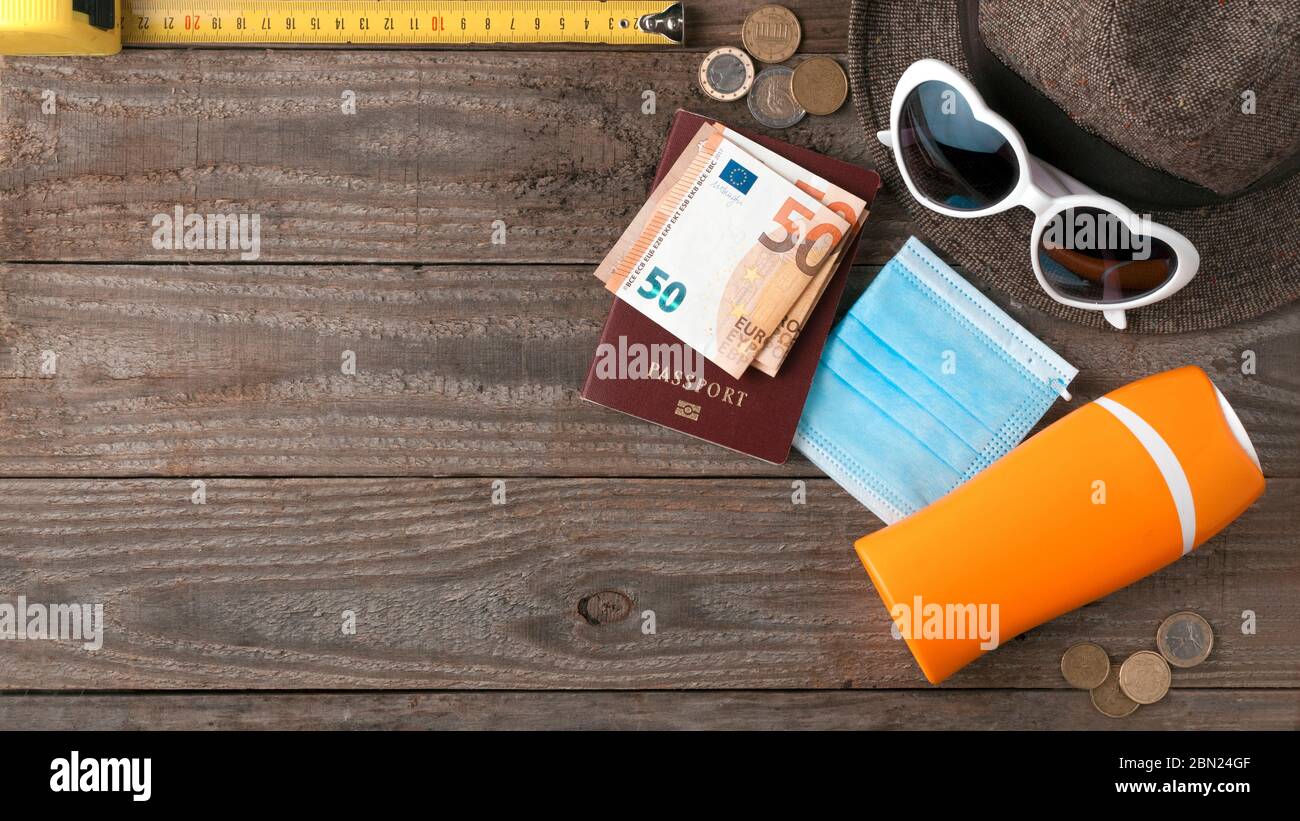 Sommer nach covid-19 Konzept: Einige Strandartikel eine chirurgische Maske und ein Meter, um die richtige soziale Distanz auf einem Holztisch zusammen mit einem Pass zu messen Stockfoto