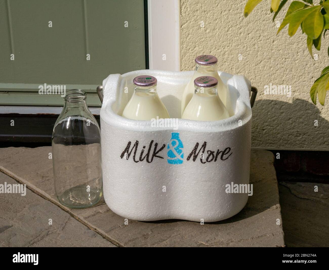 Die Nachfrage nach Milch und mehr Lieferservice nach Hause wächst während der Sperrung des Coronavirus. Bild zeigt Milchflaschen mit Milch & Mehr-Lieferbox vor der Haustür Stockfoto