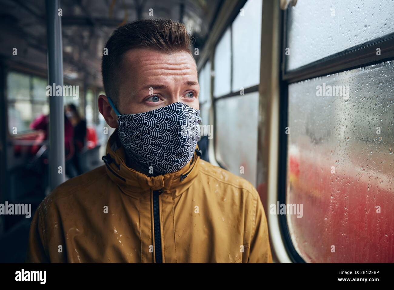 Mann mit Gesichtsmaske in öffentlichen Verkehrsmitteln. Themen soziale Distanz und persönlicher Schutz. Stockfoto