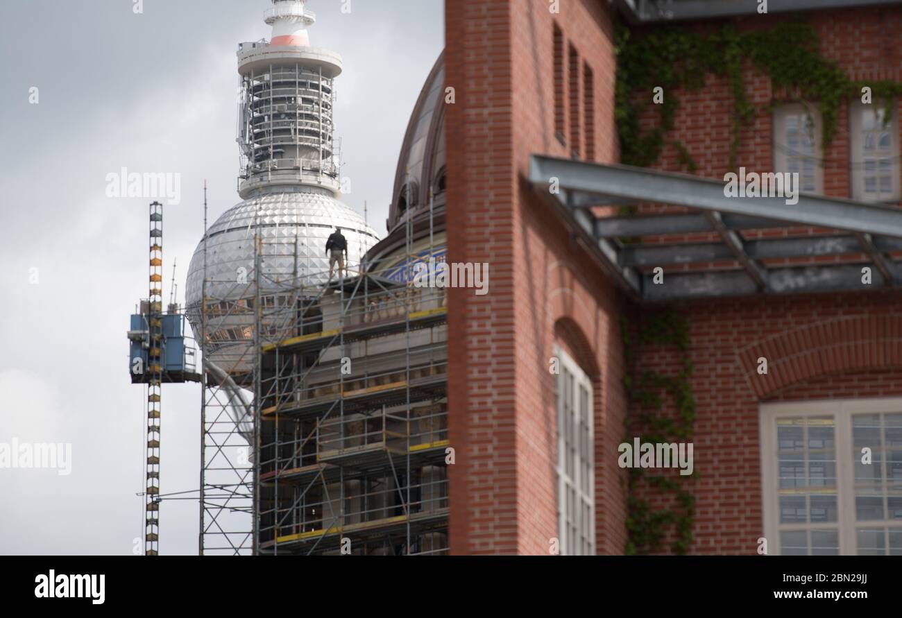 Berlin, Deutschland. Mai 2020. Ein Arbeiter steht auf einem Gerüst des unvollendeten Humboldt Forums. Aufgrund des Corona-Virus wird das Kulturzentrum im September 2020 nicht eröffnet. Im Vordergrund befindet sich ein Teil der Schinkel Akademie, im Hintergrund der Fernsehturm. Quelle: Jörg Carstensen/dpa/Alamy Live News Stockfoto