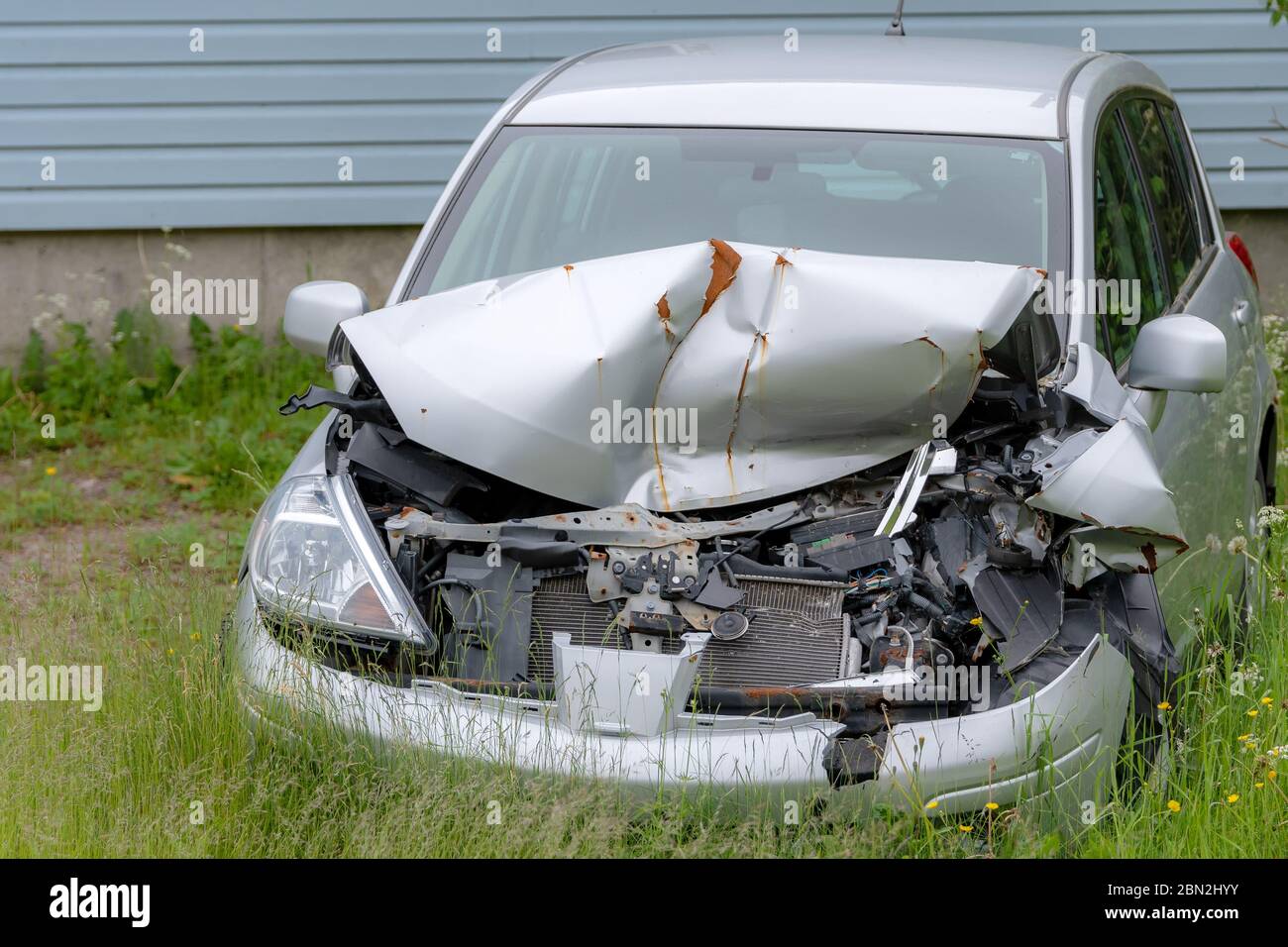 Ein kleines Auto mit der Front ist eingefahren. Es ist so zerschlagen, dass die Marke und das Modell nicht identifiziert werden können. Die Haube ist zerknittert und zerbrochene Komponente Stockfoto