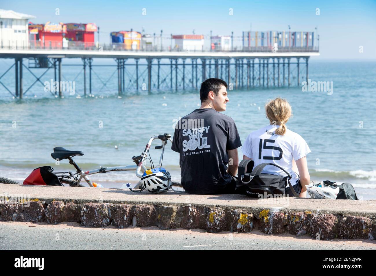Ein paar Pause von der Radtour am Meer in Paignton, Großbritannien Stockfoto