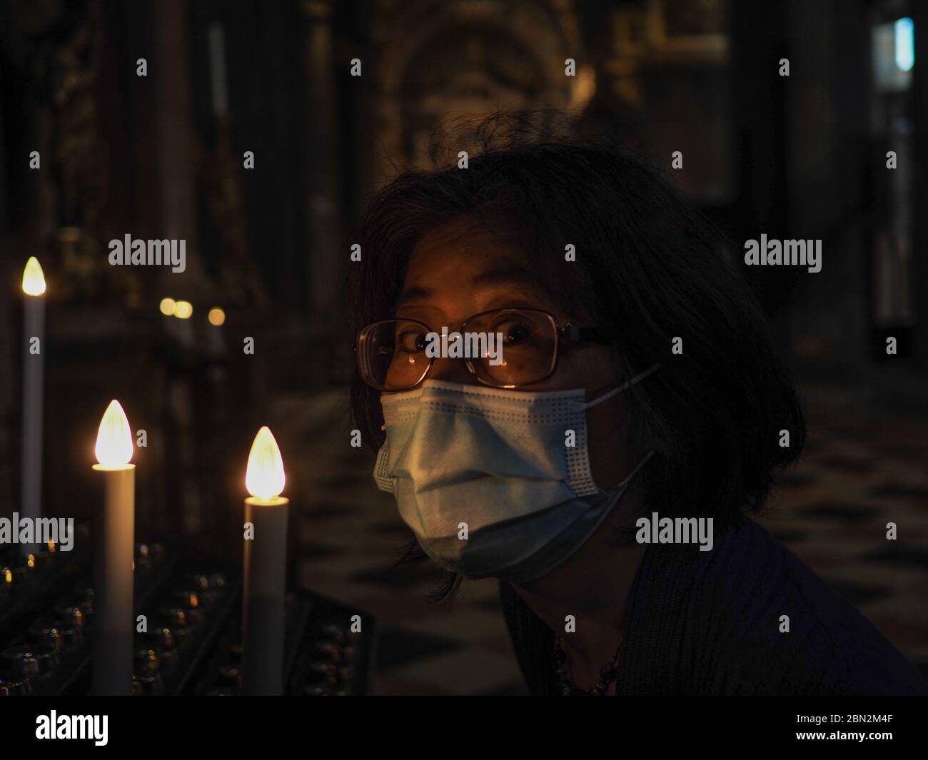 Porträt eines Erwachsenen kurzhaarige asiatische Frau mit Mund chirurgischen blauen Gesichtsmaske während covid 19 oder Corona Ausbruch und beten und Blitz eine Dose Stockfoto