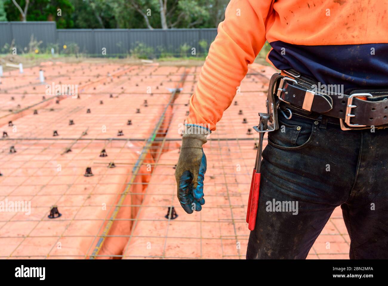 Australischer Stahlbefestigungs-Arbeiter, der mit Werkzeugen ausgerüstet ist, die auf der Baustelle an einem Tag stehen Stockfoto