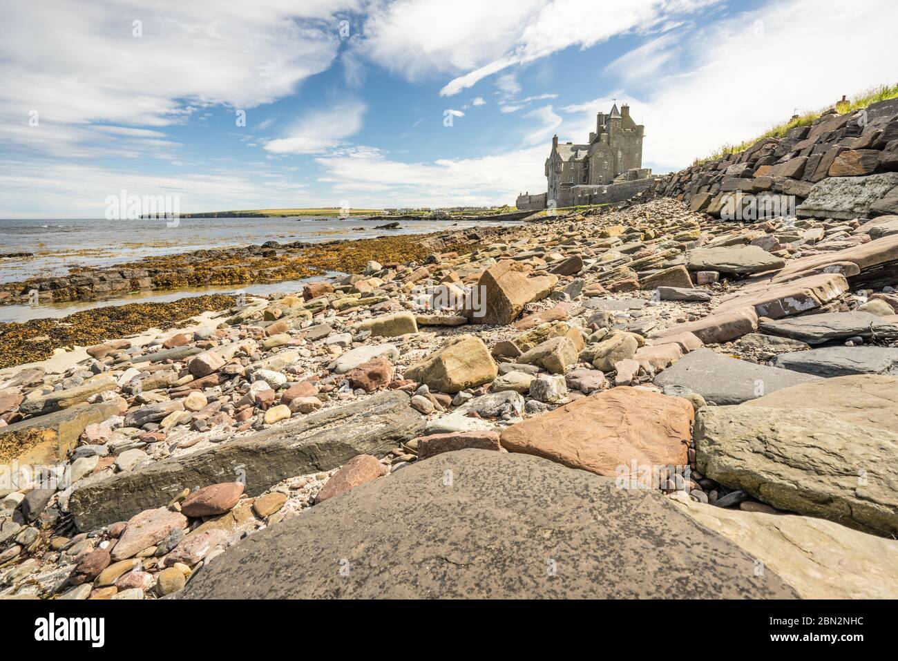 Historisches Hotel am Ackergill Tower in der Sinclair Bay in den schottischen Highlands. Felsiger Strand mit dem wunderschönen und luxuriösen alten britischen Herrenhaus in der BA Stockfoto