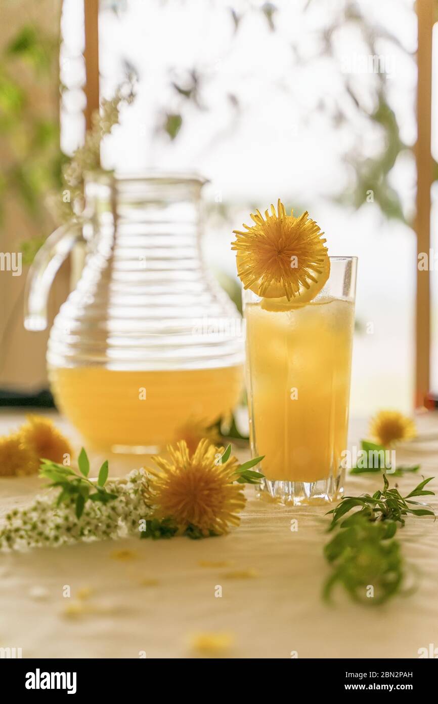 Zitrusfrüchte in einem Glas und einem Krug zwischen den Blumen auf dem Tisch, heller sonniger Morgen Stockfoto
