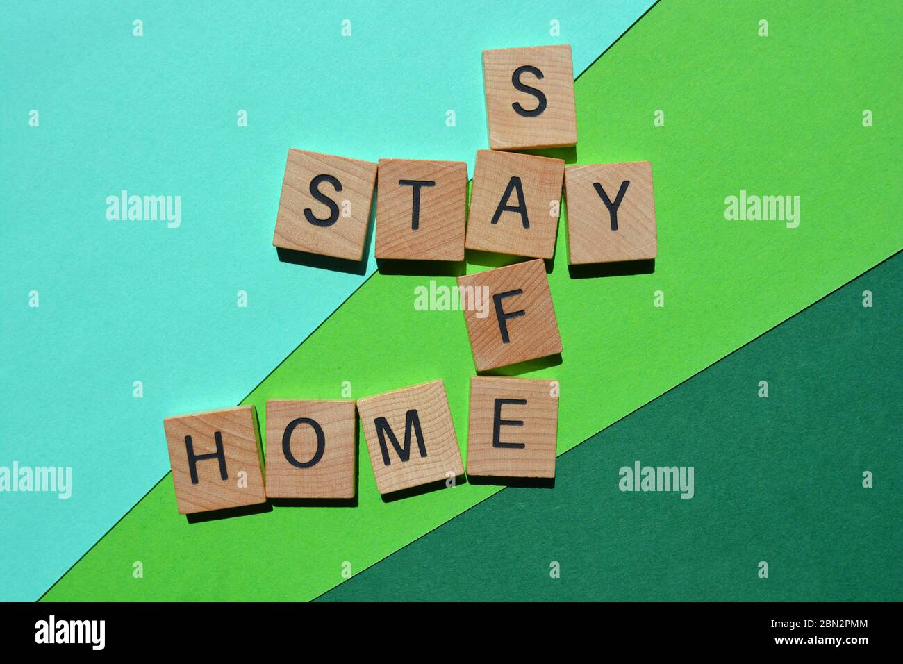 Stay, Safe, Home, Wörter in 3d Holz Alphabet Buchstaben in Kreuzworträtsel auf grün Stockfoto