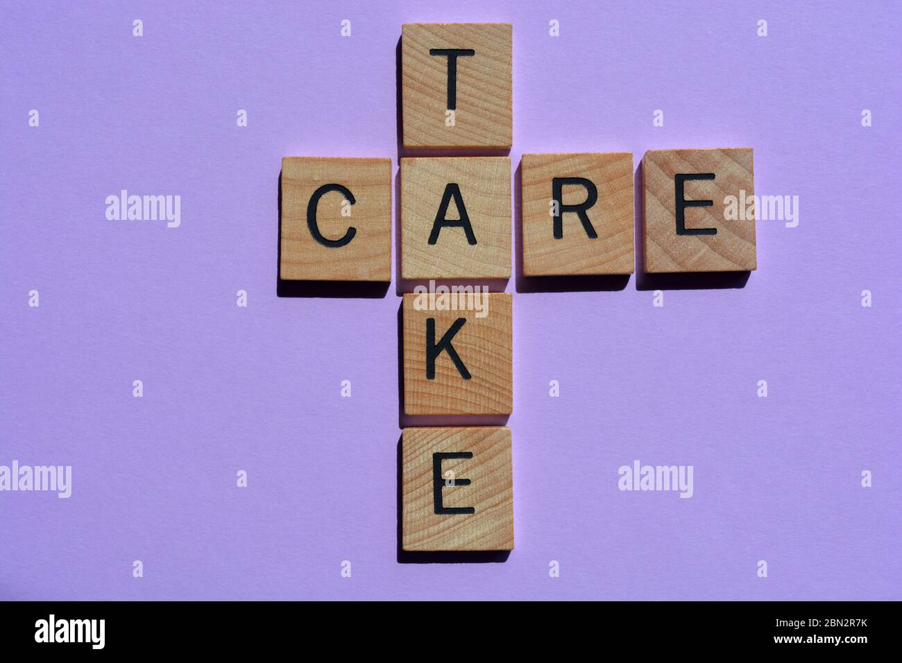 Nehmen, Pflege, Wörter in hölzernen Buchstaben Alphabet isoliert auf lila Hintergrund Stockfoto
