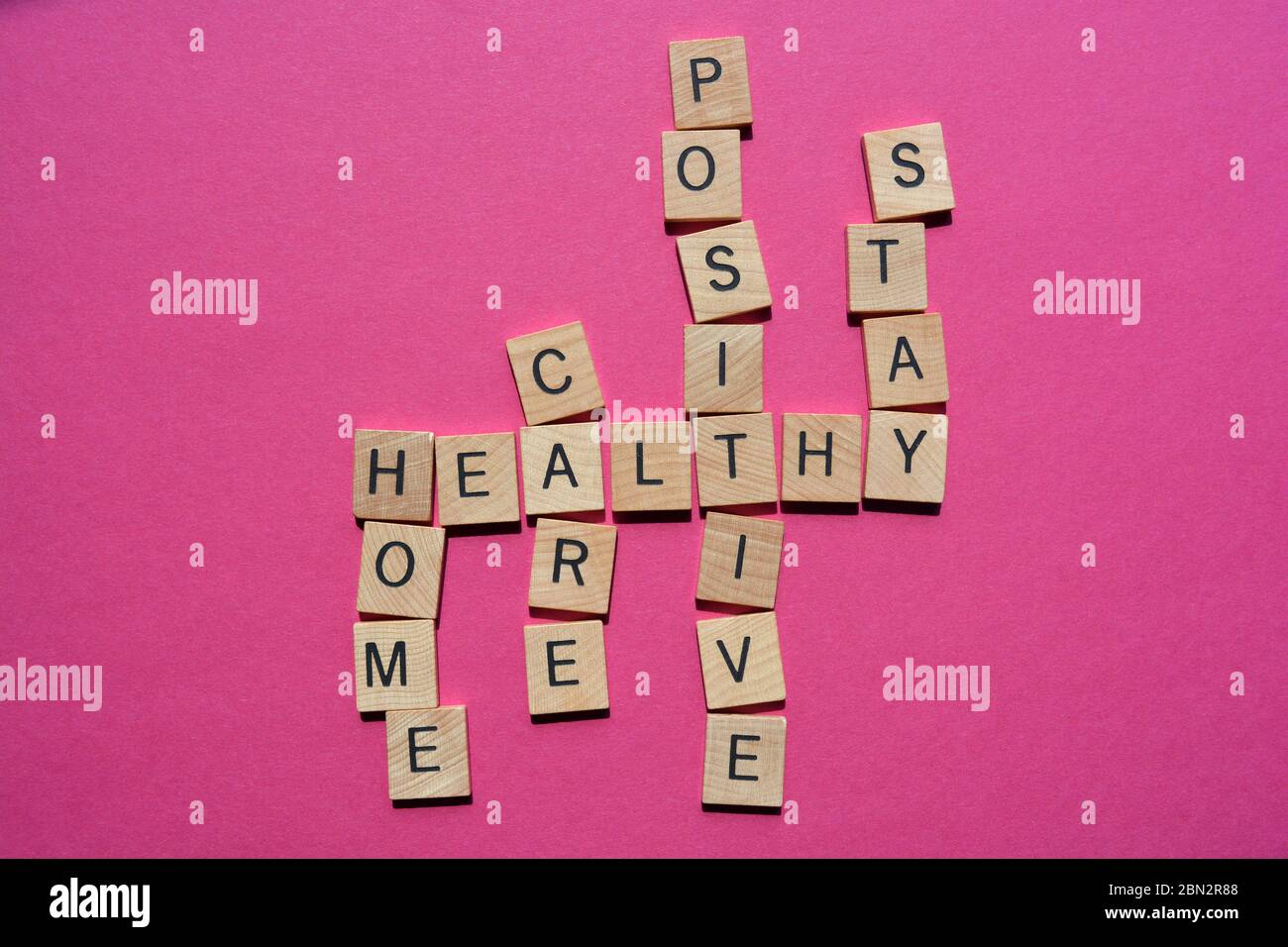 Positiv, Zuhause, Pflege, Bleiben, gesund, Kreuzworträtsel isoliert auf rosa Hintergrund Stockfoto