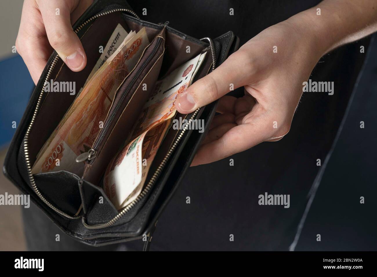 Ein Mann mit einer schwarzen Brieftasche voller russisches Geld. In einer schwarzen Brieftasche, Banknoten sind meist 5,000 Rubel pro Stück. Gehalt und Rente erhöht, Leistungen Stockfoto